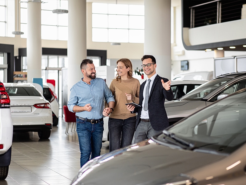 Customers touring a modern GMC dealership showroom with a sales representative at San Juan GMC